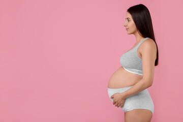 Beautiful pregnant woman in comfortable maternity underwear on pink background, space for text