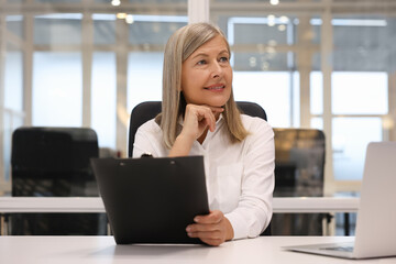 Smiling woman with clipboard working in office. Lawyer, businesswoman, accountant or manager