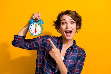 Photo of overjoyed cute woman with bob hairdo dressed plaid shirt indicating at clock open mouth...