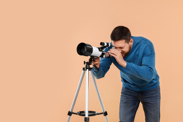 Astronomer looking at stars through telescope on beige background. Space for text