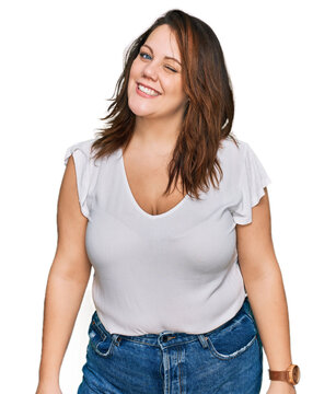 Young plus size woman wearing casual white t shirt winking looking at the camera with sexy expression, cheerful and happy face.