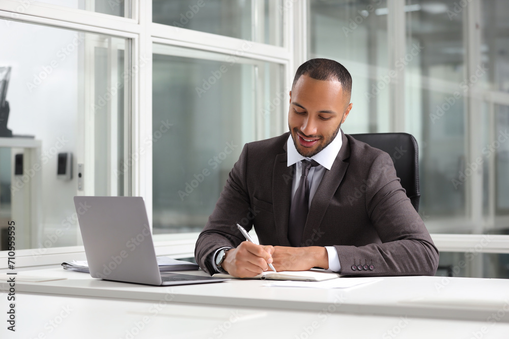 Wall mural Happy man working at table in office. Lawyer, businessman, accountant or manager