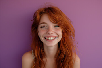 Closeup of happy attractive young woman with long wavy red hair and freckles wears stylish t shirt looks happy and smiling isolated over purple background.