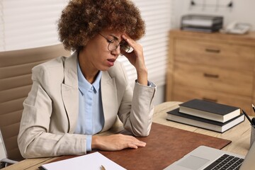 Woman suffering from headache at workplace in office