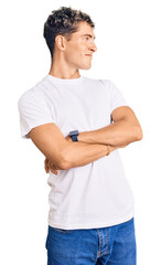 Young handsome man wearing casual white tshirt looking to the side with arms crossed convinced and confident