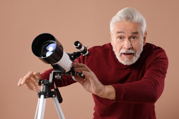 Senior astronomer with telescope on brown background