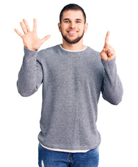Naklejka premium Young handsome man wearing casual sweater showing and pointing up with fingers number six while smiling confident and happy.
