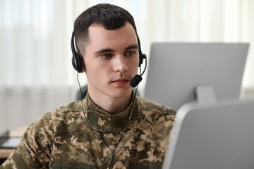 Military service. Young soldier in headphones working in office