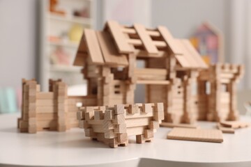 Wooden entry gate and building blocks on white table indoors, selective focus. Children's toy