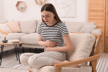 Fototapeta premium Young woman suffering from stomach pain at home