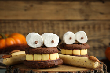 Delicious desserts decorated as monsters on stump, closeup. Halloween treat