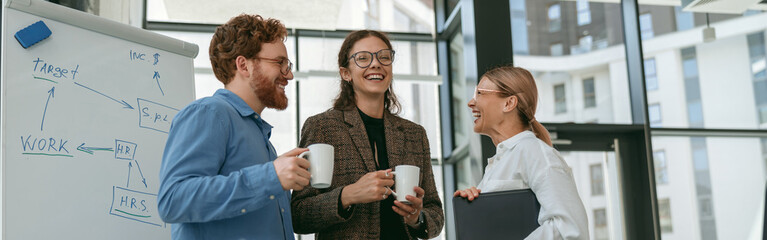 Smiling business team resting and talking during coffee break time in office meeting room