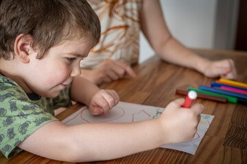 Niño dibujando junto a su mamá escribiendo una carta navideña a papá noel