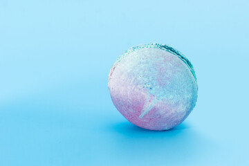 Blue French macaroon on light blue background. Tasty colorful macarons. Cookie made of two smooth halves, fastened with stringy fillings. French pastry made from egg whites.