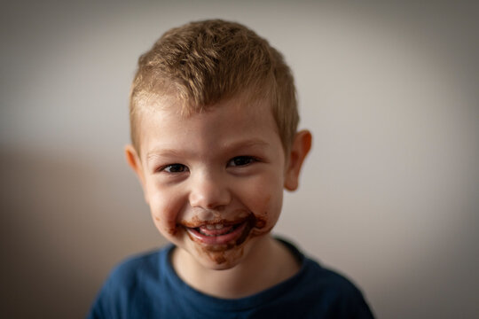 Retrato de niño rubio sonriendo con la boca sucia de chocolate
