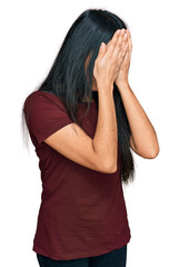 Young hispanic girl wearing casual t shirt with sad expression covering face with hands while crying. depression concept.