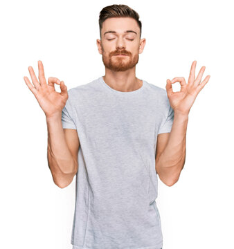 Young redhead man wearing casual grey t shirt relax and smiling with eyes closed doing meditation gesture with fingers. yoga concept.