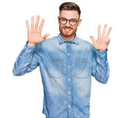 Naklejka premium Young redhead man wearing casual denim shirt showing and pointing up with fingers number nine while smiling confident and happy.