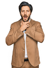 Young hispanic man wearing business clothes shouting suffocate because painful strangle. health problem. asphyxiate and suicide concept.