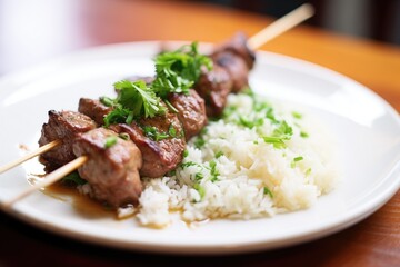 close-up of beef kebab plated with rice and parsley