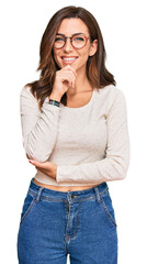 Obraz premium Young brunette woman wearing casual clothes and glasses with hand on chin thinking about question, pensive expression. smiling with thoughtful face. doubt concept.