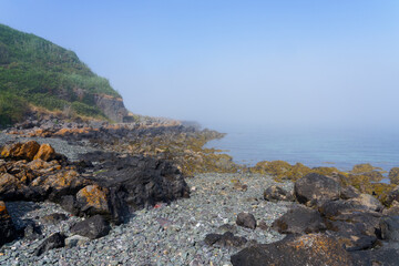 Fototapeta na wymiar On the rocky foreshore of Porthdinllaen bay in Wales on a foggy summer afternoon.