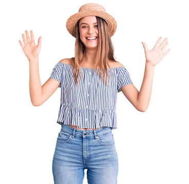 Young beautiful girl wearing hat and t shirt showing and pointing up with fingers number ten while smiling confident and happy.