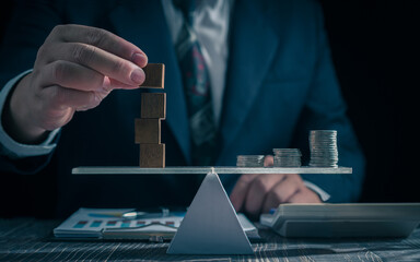 Economic risk management concept. Businessman holding wooden block . With level coin balance,...