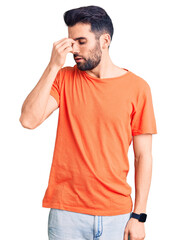 Young handsome man with beard wearing casual t-shirt tired rubbing nose and eyes feeling fatigue and headache. stress and frustration concept.