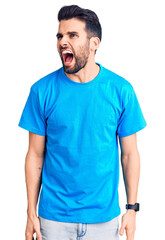 Fototapeta premium Young handsome man with beard wearing casual t-shirt angry and mad screaming frustrated and furious, shouting with anger. rage and aggressive concept.