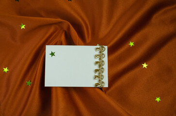 Textured brown background with writing card with gold decoration, shiny stars scattered around