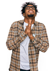 Young african american man with beard wearing casual clothes and glasses begging and praying with hands together with hope expression on face very emotional and worried. begging.