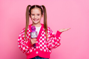 Photo of cheerful charming girl wear trendy clothes arm demonstrate novelty announces news empty space isolated on pink color background