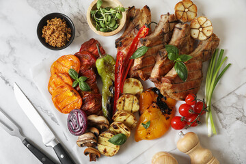 Delicious grilled meat and vegetables served on white marble table, flat lay