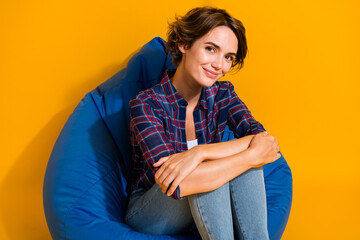 Portrait of gorgeous adorable girl wear checkered blouse sitting on blue pouf embrace her knees...