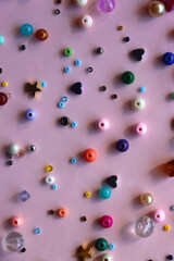 Various colorful beads on bright pink background. Top view.