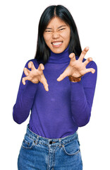 Beautiful young asian woman wearing casual clothes smiling funny doing claw gesture as cat,...