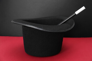 Black top hat and wand on color background. Magician equipment
