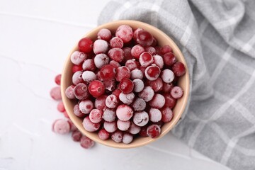 Frozen red cranberries in bowl on white table, top view