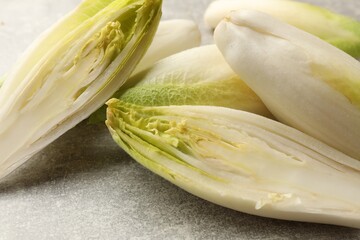 Fresh raw Belgian endives (chicory) on light grey table, closeup