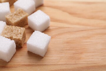 White and brown sugar cubes on wooden table, closeup. Space for text