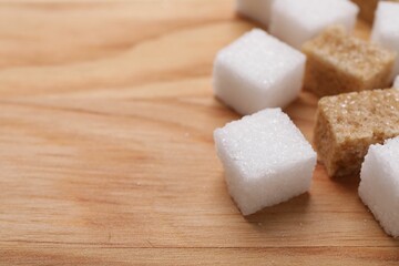 White and brown sugar cubes on wooden table, closeup. Space for text