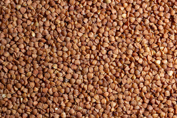 Dry Uncooked Brown Buckwheat Groats Background - Top View, Flat Lay. Raw Large Buckwheat Grains. Russian, Ukrainian and Belarusian Culture