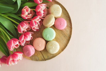 Bouquet of pink tulips and macaroons on pink background. Anniversary celebration concept. Copy space. Top view