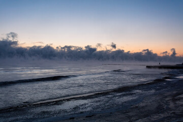Fog lifting off Lake Michigan on bitterly cold morning as sun rises - 710600317
