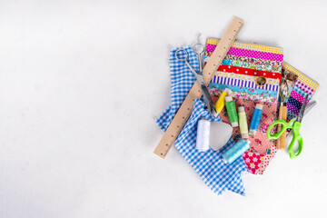 Sewing, needlework and clothing repair, background, scrapbooking, quilting. Colorful pieces of fabric, scissors, ruler, sewing tools, needles, threads on a white table background top view copy space