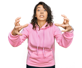 Young hispanic woman wearing casual sweatshirt shouting frustrated with rage, hands trying to strangle, yelling mad