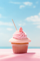 Cupcake with pink frosting on a pink sand on a beach.Pastel pink and blue color.
