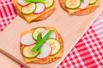 Light Breakfast. Quick and Healthy Sandwich. Fresh Cucumber and Radish with Green Onions and Cheese on Crispy Cracker on Wooden Cutting Board