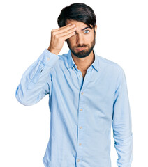 Hispanic man with blue eyes wearing business shirt worried and stressed about a problem with hand on forehead, nervous and anxious for crisis